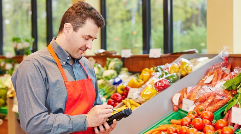 Ein Supermarktmitarbeiter nutzt ein MDE-Gerät zur Bestandskontrolle im Obst- und Gemüsebereich.