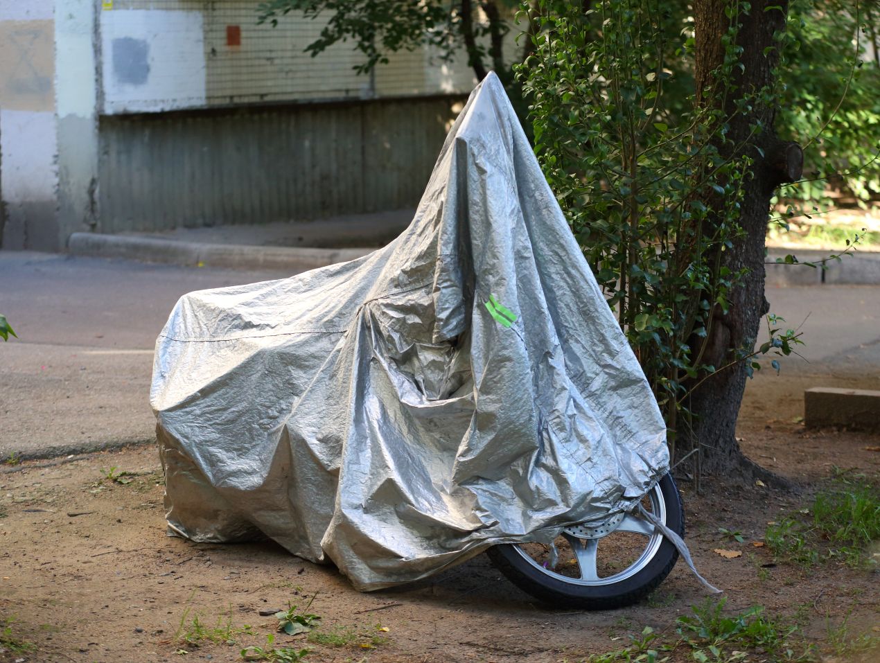 Motorrad mit einer wasserdichten Plane abgedeckt, um es vor Regen und Witterungseinflüssen zu schützen – effektiver Motorrad Schutz im Alltag.